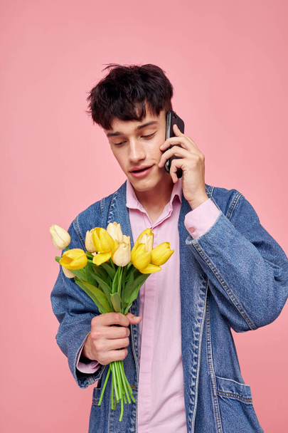 young guy with a bouquet of flowers talking on the phone date gift - Zdjęcie, obraz