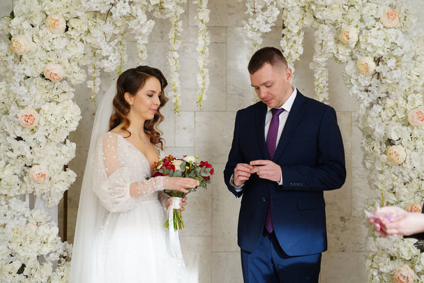 exchange wedding rings.bride and groom in an arch of flowers at wedding ceremony - Zdjęcie, obraz
