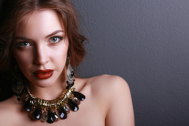 Portrait of young beautiful brunette woman in ear-rings, beads - Zdjęcie, obraz
