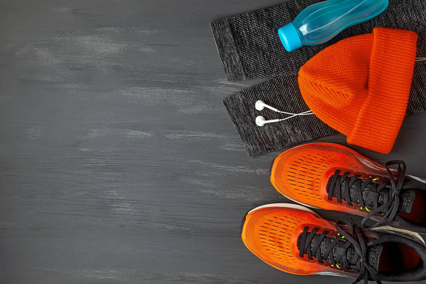 Orange knitted warm hat, warm sports leggings, headphones, water bottle and orange sneakers - Photo, image