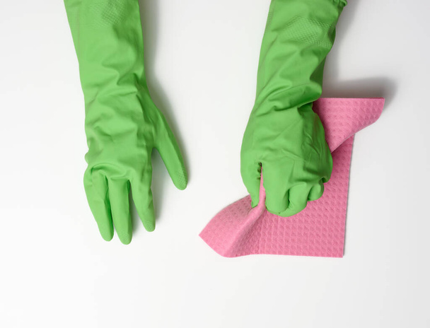 рука в зеленой резиновой перчатке держит мягкую губку для очистки поверхностей на белом фоне - Фото, изображение