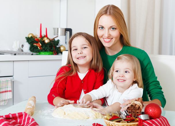 Two adorable girls with mother baking Christmas cookies in the k - Photo, Image