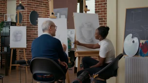 Nainen selittää vanhempi mies miten piirtää malli kankaalle - Materiaali, video