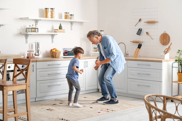 A kisfiú a nagyapjával táncol a konyhában. - Fotó, kép