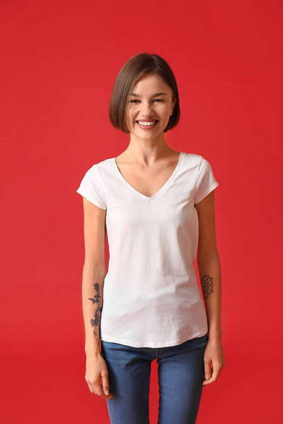 Krásná mladá žena ve stylovém tričku na barevném pozadí - Fotografie, Obrázek