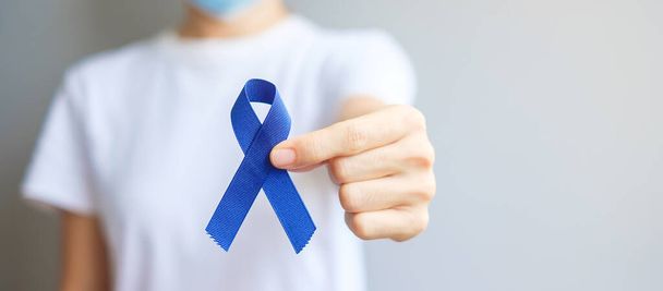 Март Месяц Награждения за Красочный Рак, Женщина, держащая темно-синюю ленту для поддержки людей, живущих и больных. Здравоохранение, надежда и Всемирный день борьбы с раком - Фото, изображение