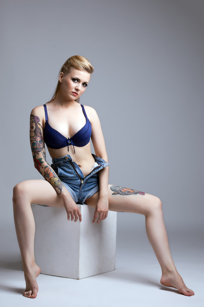 Curvy tattooed model posing sitting on cube - Foto, imagen
