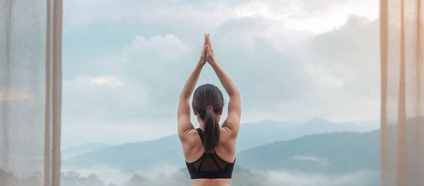Młoda dorosła kobieta w odzieży sportowej uprawiająca jogę i rozciągająca się ciało przed widokiem na góry, zdrowa kobieta medytująca rano. wellness, fitness, Vitality, ćwiczenia i równowaga życia zawodowego - Zdjęcie, obraz
