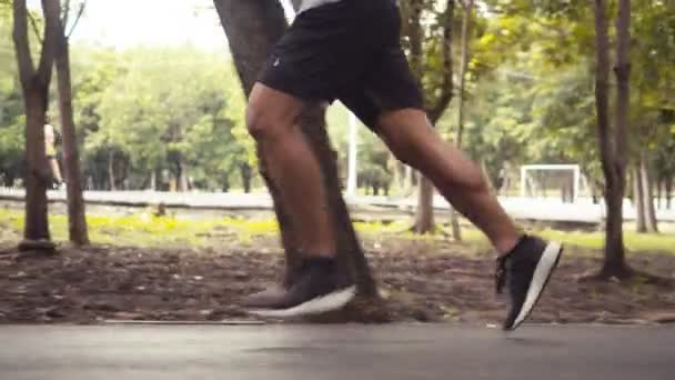 Close up legs authentic Asian man running in the public park. athlete exercise training workout healthy outdoors concept. Slow-motion movement. - Záběry, video