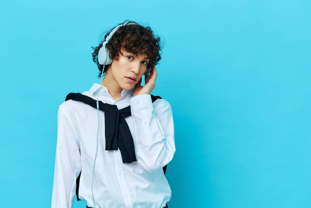 curly guy technology headphones in a white shirt with sweater blue background - Photo, Image