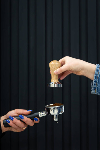 Female hands hold a holder with coffee and temperature on a black background. - Photo, Image