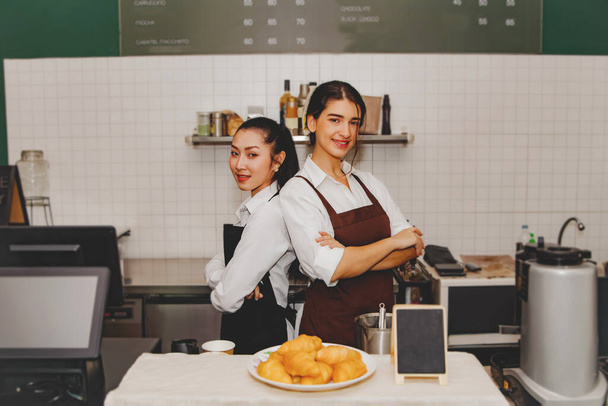 Portrait two gorgeous baristas welcome orders in a trendy cafe. Serving a smiling coffee shop business with impressive friendsh : Coffee shop franchise business, food and beverage concept. - Photo, Image