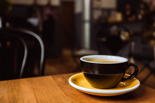 A ceramic cup of black coffee on the wooden table in a cafe. - Fotoğraf, Görsel