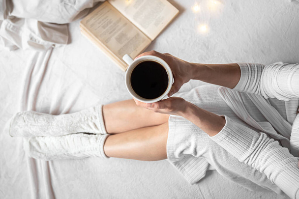 Egy csésze kávé női kezekben az ágyban, felülnézet. - Fotó, kép