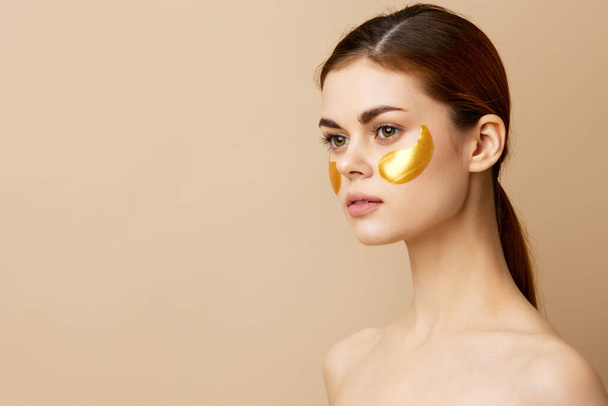 portrait woman skin care face patches bare shoulders hygiene beige background - Fotó, kép