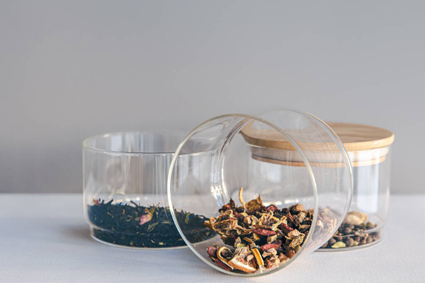 Different types of tea in glass jars on a light background, isolated. - Fotó, kép