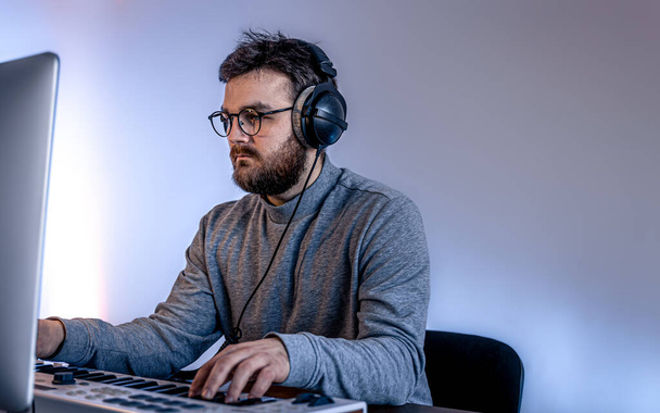 Mannelijke muzikant maakt muziek met behulp van computer en toetsenbord, muzikant werkplek. - Foto, afbeelding