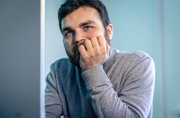 Втомлений бородатий чоловік дивиться на екран комп'ютера
. - Фото, зображення