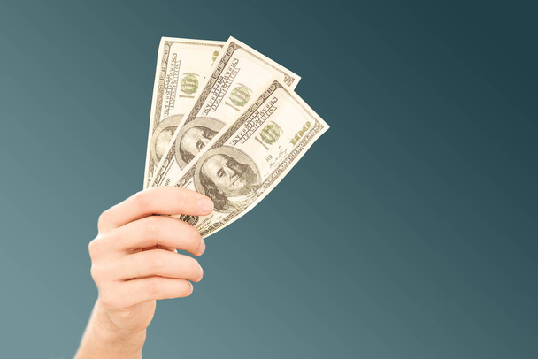Hands holding 100 dollar bills. Mens hand holds a fan of dollars. Wealth, financial flows and success. - Fotografie, Obrázek