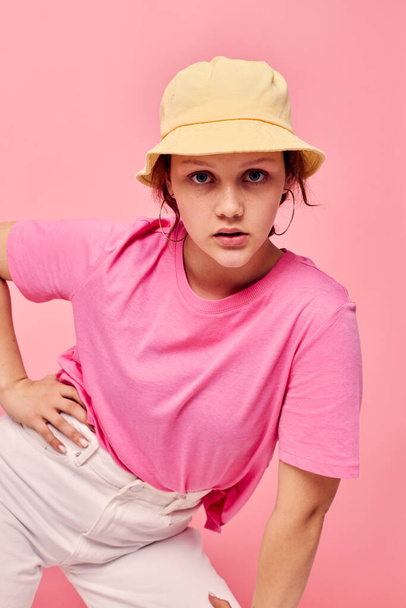Young woman in a pink T-shirt and hat Youth fashion pink color background  - Zdjęcie, obraz