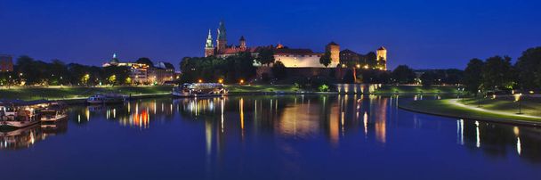 Krakow, Poland - June 18, 2019: Panorama of Wawel Castle on Wawel Hill with reflection in the Vistula river at night. Krakow is the second-largest and one of the oldest cities in Poland. - Фото, зображення