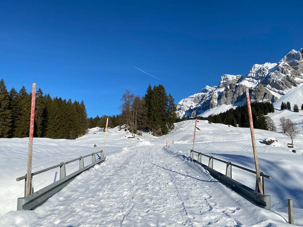 アペンツェル・アルプス塊のアルプシュタイン山の麓にある穏やかな高山の谷で、新鮮な雪の冬のカバーの下で地元の山岳道路-スイス(スイス)) - 写真・画像