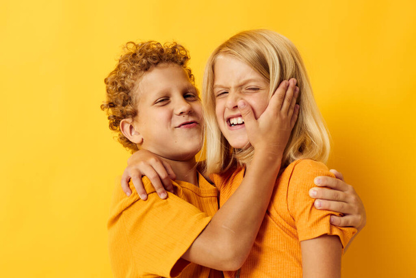 Small children in yellow t-shirts standing side by side childhood emotions yellow background - Foto, Imagem