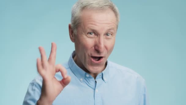 Seniorský souhlas. Šťastný emocionální starší šedovlasý muž ukazující OK gesto fotoaparátu a úsměv - Záběry, video
