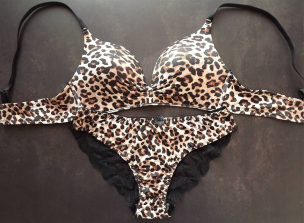 Conjunto de lencería de leopardo con bragas de encaje sobre fondo negro - Foto, Imagen