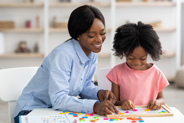 Веселая, симпатичная американка из Африки учит маленьких девочек алфавиту. - Фото, изображение