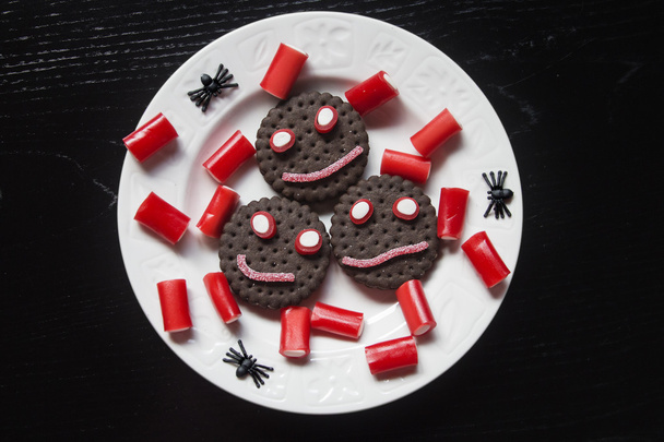 lächelnde Plätzchen mit Bonbons und Spinnen bei der Halloween-Feier - Foto, Bild