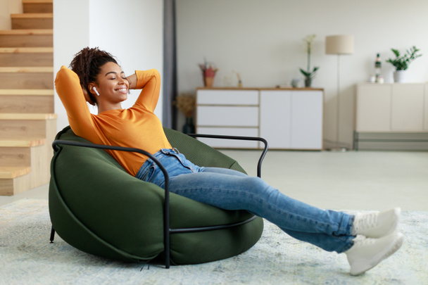 Ruhige schwarze Frau, die sich zu Hause auf einer Sitzsäcke ausruht - Foto, Bild