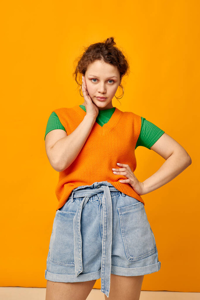 portrait of a young girl in an orange sweater denim shorts - Φωτογραφία, εικόνα