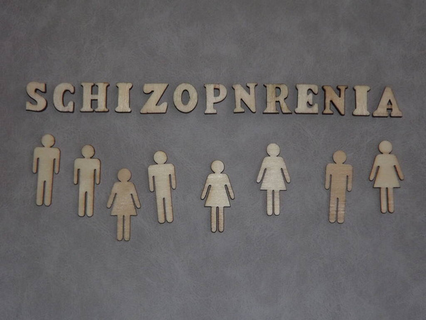 mentális betegség-skizofrénia formájában fa betűk és figurák az emberek szürke alapon - Fotó, kép