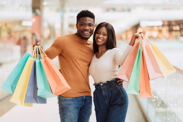 Hermosa pareja negra sosteniendo bolsas de compras mirando a la cámara - Foto, Imagen