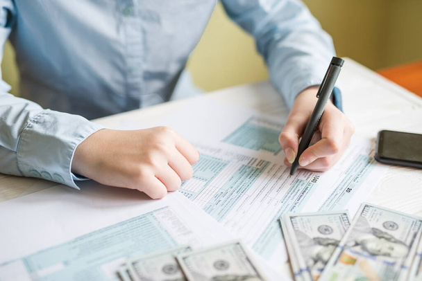 Großaufnahme einer Frau, die an einem Tisch ein Formular von 1040 ausfüllt. Steuerkonzept, Finanzdokument - Foto, Bild