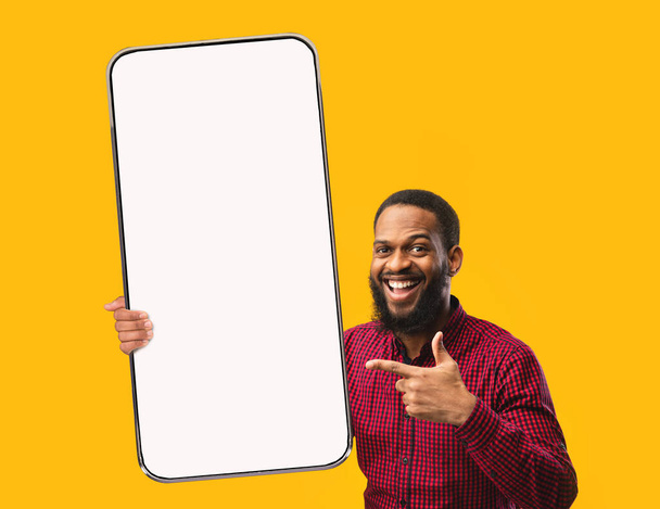 Черный парень указывает на белый пустой экран смартфона - Фото, изображение