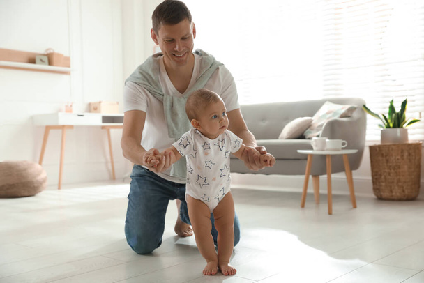 Father supporting his baby daughter while she learning to walk at home - Valokuva, kuva