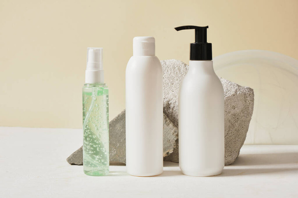 three different mockup bottles with cosmetics on the background of stones and a stand, presentation of your natural product - Photo, image
