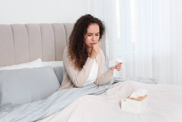 Sick African American woman with box of tissues in bed at home - Valokuva, kuva