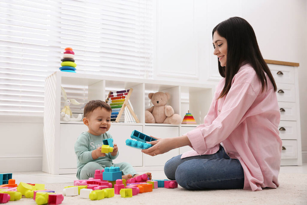 Cute baby boy playing with mother and building blocks on floor at home - Foto, immagini