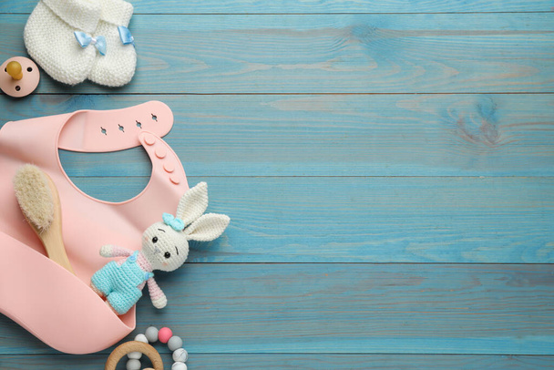 Flat lay composition with silicone baby bib, toys and accessories on light blue wooden background. Space for text - Φωτογραφία, εικόνα
