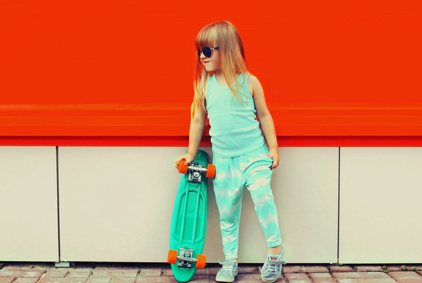 Portrait of stylish little girl child with skateboard on city street - Foto, Imagem