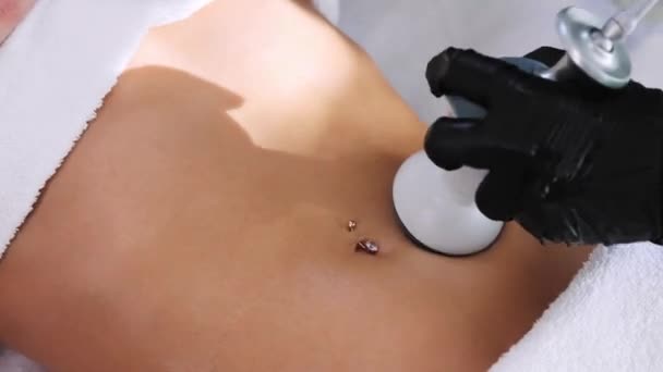 Massaggio elettrico del corpo - terapeuta che utilizza un dispositivo sullo stomaco con piercing del suo cliente donna - Filmati, video