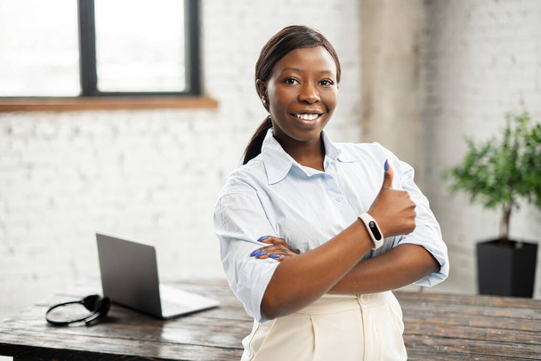 Portrait of confident African businesswoman with arms crossed and showing thumb up - Фото, зображення