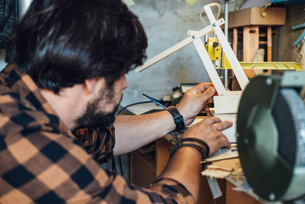 Невпізнаваний інженер збірки роботів рука. Анонімний чоловік робить дерев'яну роботизовану руку в своїй майстерні
. - Фото, зображення