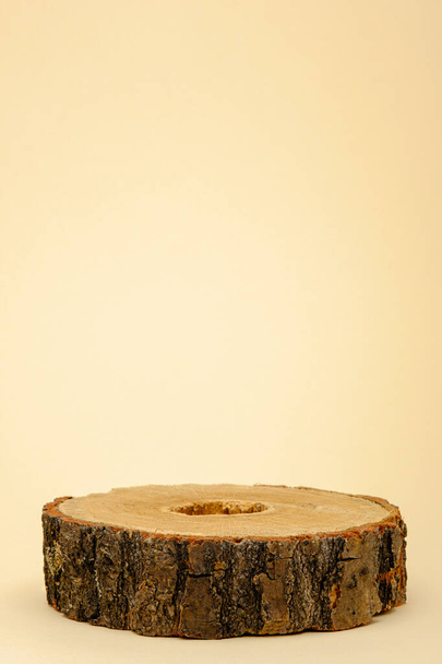κατακόρυφο ξύλινο βάθρο για παρουσίαση καλλυντικών οικολογικής ομορφιάς, ένα στρογγυλό πριόνι σε μπεζ φόντο - Φωτογραφία, εικόνα