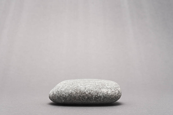 egy szürke kő, kavicsos dobogó szürke alapon a termék bemutatásához sugarakkal - Fotó, kép