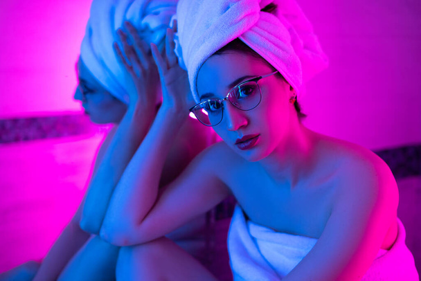 Gözlüklü kız banyoda neon ışıkta havluyla - Fotoğraf, Görsel