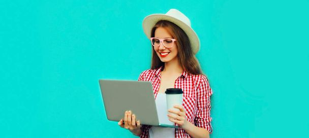 Portrait of modern young woman working with laptop on blue background - Fotografie, Obrázek